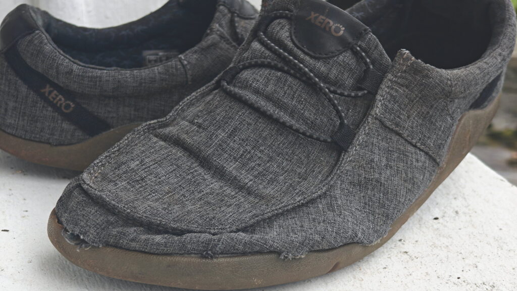 Heavily worn Xero Shoes with fraying around the toe
