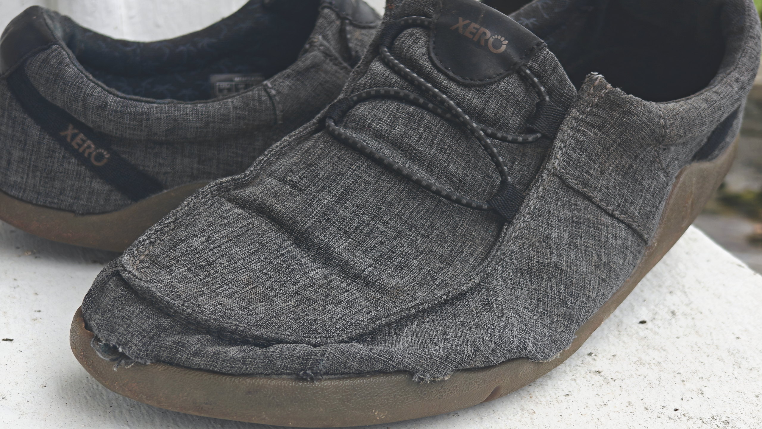 Heavily worn Xero Shoes with fraying around the toe