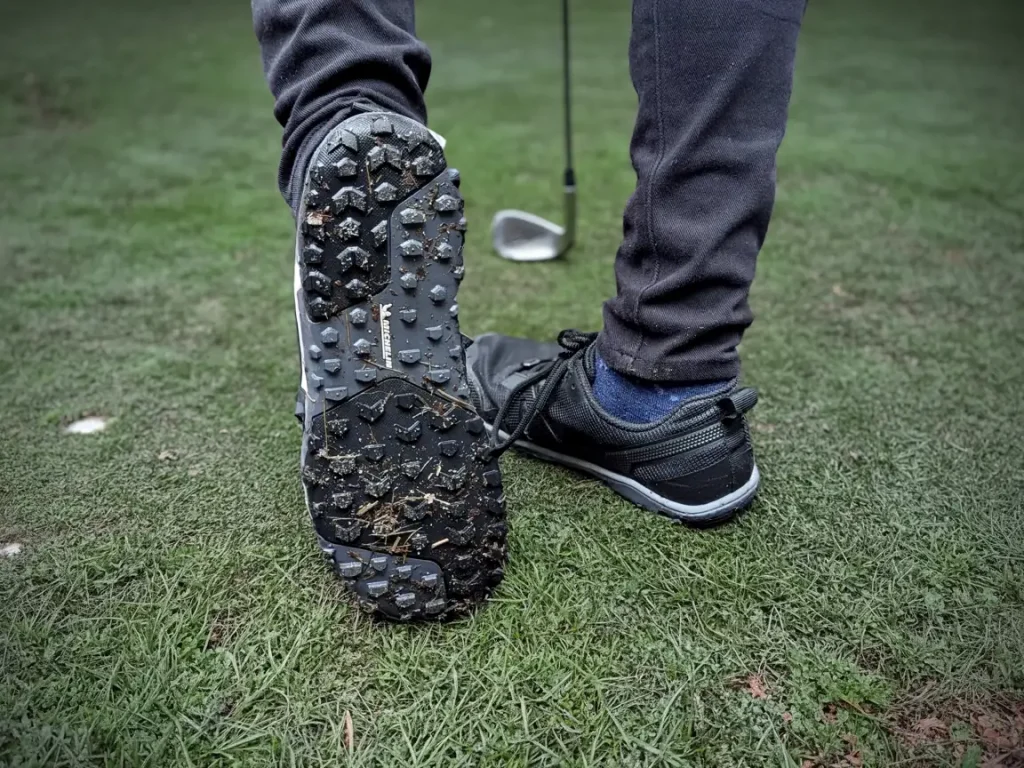 close-up of Xero Shoes Scrambler Low EV sole while walking on a golf course next demonstrating grip while carrying a golf club