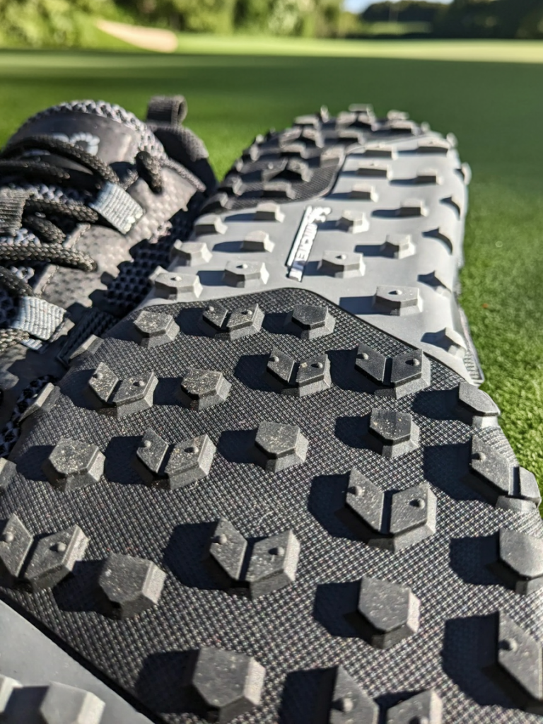 close-up image of the xero shoes scrambler low ev beefy lugs with the golf course in the background