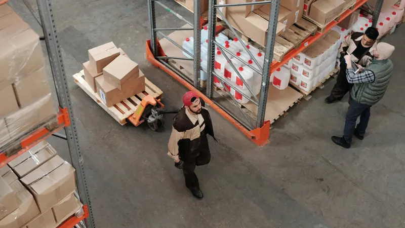 Overhead view of warehouse workers on concrete floors showing demanding work environment for barefoot shoes