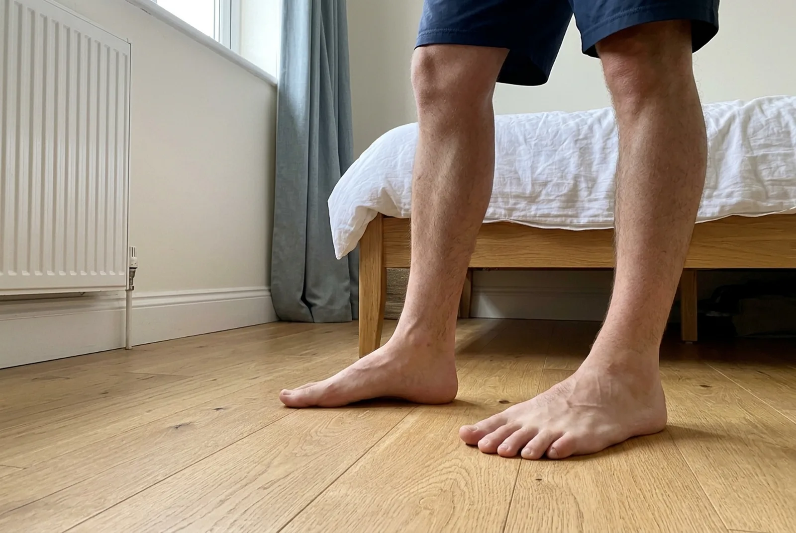 Man standing barefoot with the arch of one foot domed upward, doing the short-foot exercise